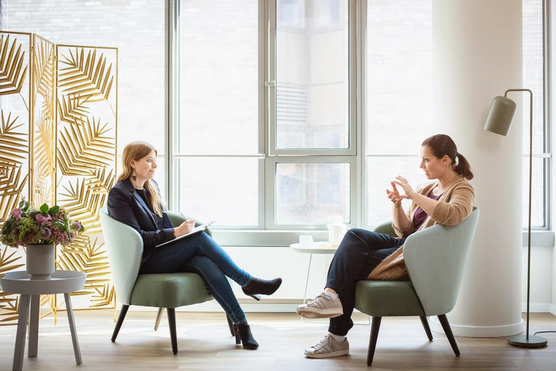 Therapeuting spricht mit patientin im gro&szlig;en raum, beide sitzen gegen&uuml;ber